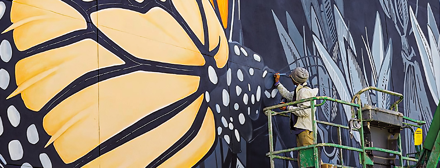 Photo of a person painting a mural of a butterfly