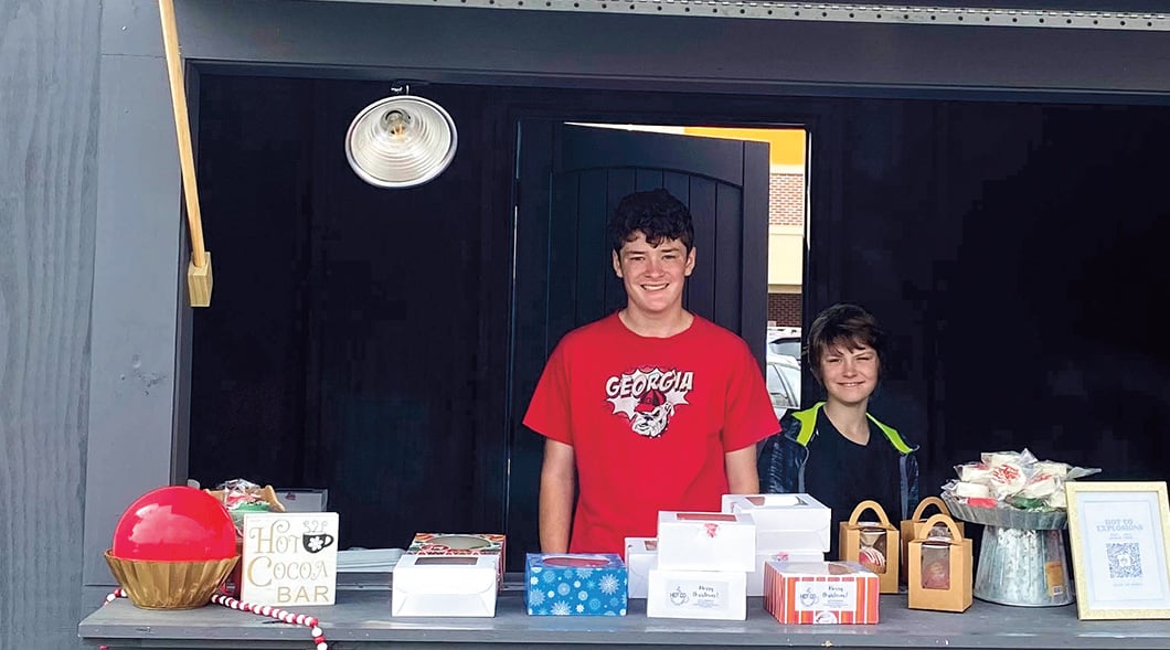 Image of two people posing behind a hot chocolate stand