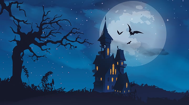 A haunted castle with lit windows stands before a full moon with bats in a night sky